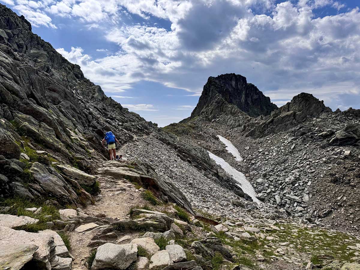 Randonneur progressant dans le terrain rocheux du col du Brévent sur le Tour du Mont-Blanc